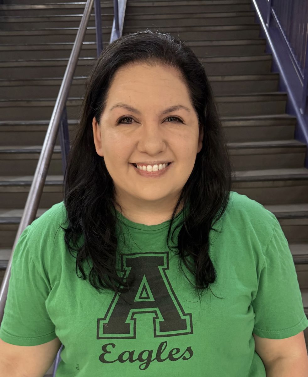 Image is of the Wellness counselor. She is brunette and smiling, and is wearing a bright green shirt with a large A and eagles written below it.