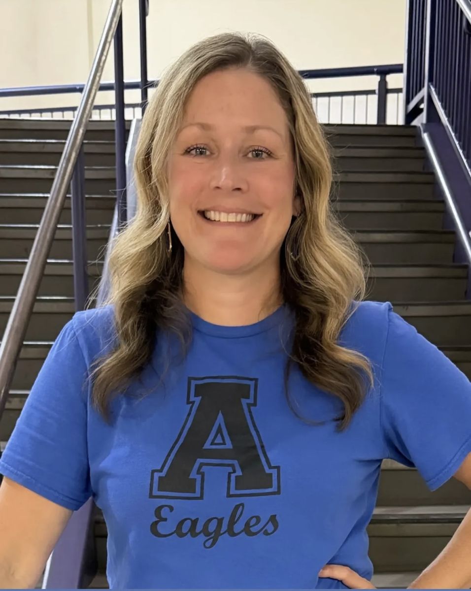 Image is of the ABLLE counselor. She is blonde and smiling, and is wearing a bright, blue shirt with a large A and eagles written below it.